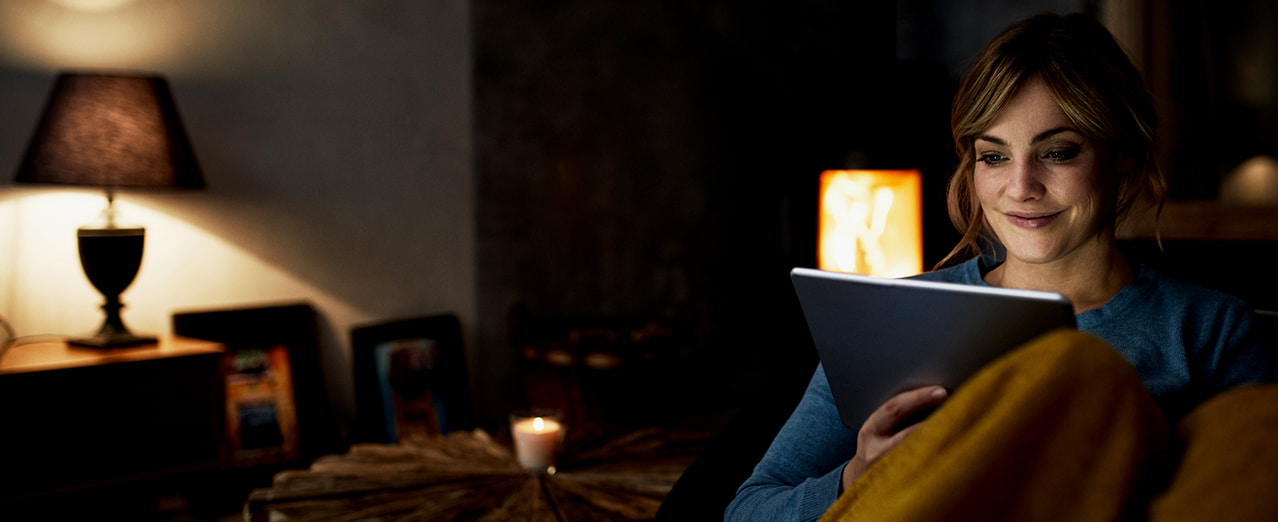 Woman looking at a tablet on a sofa.