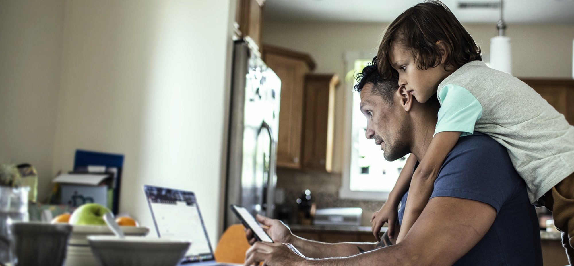 An image of a man with a child looking at his laptop.